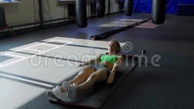 运动垫上的女运动员在健身房做腹肌锻炼。 肌肉女运动员做腹肌锻炼。
